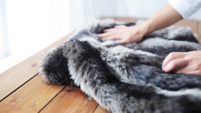 woman folding faux fur jacket on table at home
