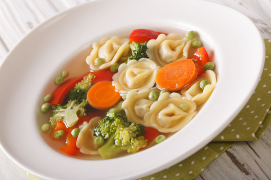 Hot tortellini soup with broccoli, peas, carrot and pepper close-up. Horizontal