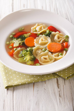 Hot tortellini soup with broccoli, peas, carrot and pepper close-up. vertical
