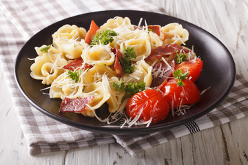 Italian cuisine: tortilini with ham, tomatoes, herbs and cheese closeup. horizontal