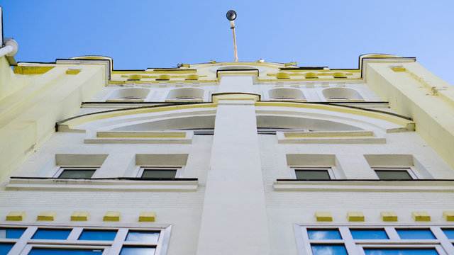 Point Of View From The Ground Into The Blue Sky On Office Building And Security Camera On The Top Roof