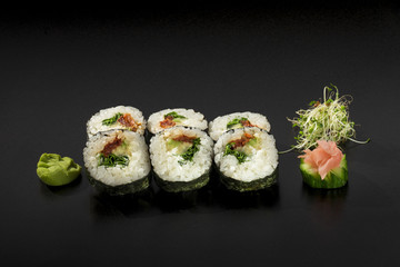 Japanese sushi rolls decorated with seaweed salad and wasabi