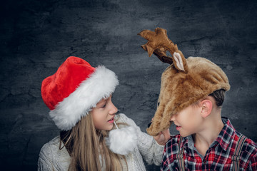 A boy and a girl in christmas hats.