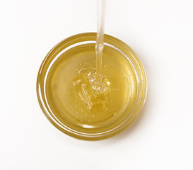Delicious sweet honey flowing down in small glass bowl.