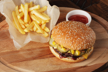 Burger (hamburger) with french fries and sauce. Wooden background.