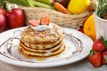 stack of homemade pancake with maple syrup and strawberry toppin