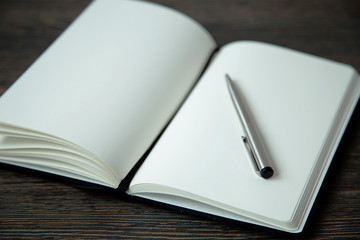 Notebook and the pen for records on a wooden background