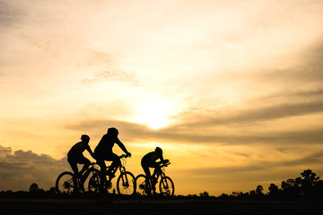 Obraz premium Silhouette of cyclist with friend motion on sunset background
