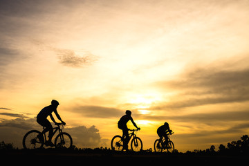 Silhouette of cyclist with friend motion on sunset background