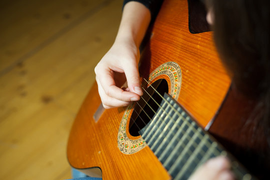 Young woman playing on the old wood guitar and enjoying nice tim