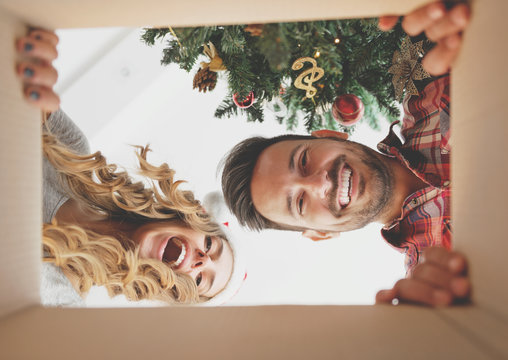 Young Couple Opening A Christmas Present, View From Inside Of The Box