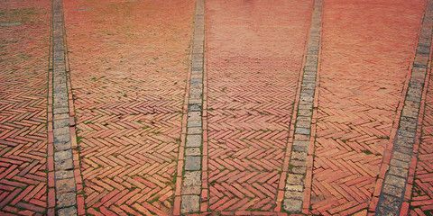 Brick pavement. Historic center of Siena. Piazza del Campo. Old zigzag pavement with grass growing...