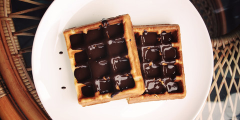 Vienna Waffles. Chocolate topping. Aged. View from the Top. White plate with Chocolate covered Wafers. Toned. Tasty dessert. Wide photo for wallpaper or site slider. Unhealthy but delicious.