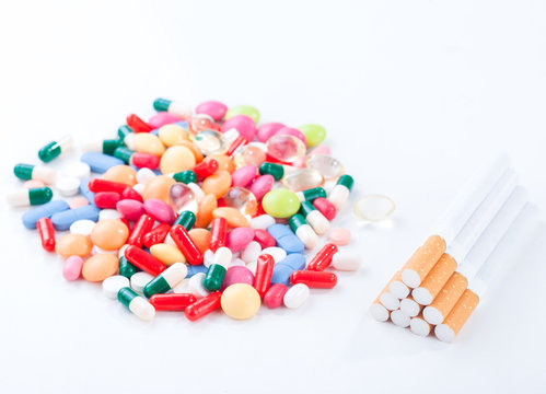 Cigarettes colorful pills and tablets on a white background