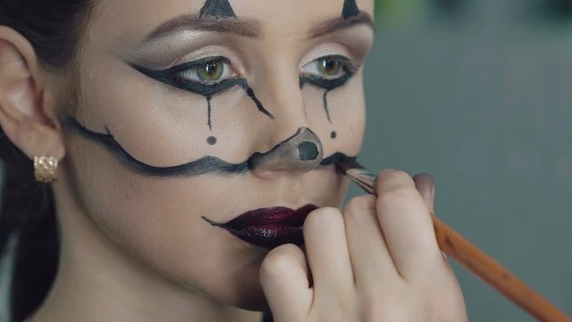 Artist drawing girl halloween makeup in art studio