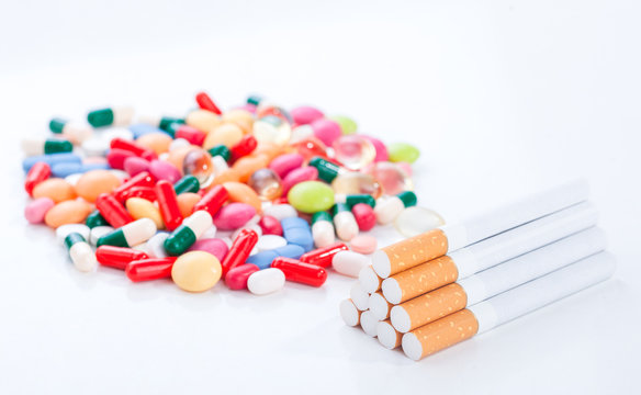 Cigarettes colorful pills and tablets on a white background