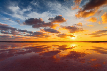 Beautiful cloudy sky above salt water lake. Scenic sunset landscape.