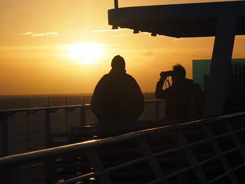 menschen im Sonnenuntergang an der schiffsreling 