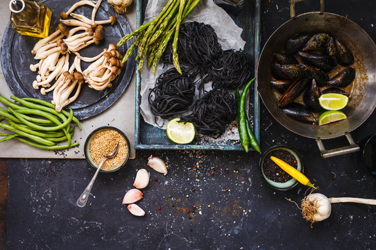Dinner fresh ingredients with freshly mussels, vegetables and black pasta.