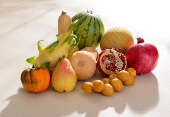 collection of tropical fruits with mini watermelon, mini melon, mini pumpkin and grapes on the white table