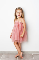 Funny little girl in a pink dress on white background