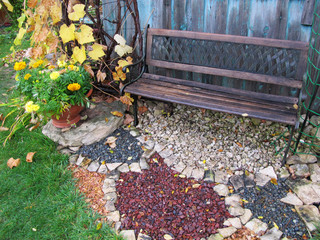 Bench and ornamental gravel in the late autumn rainy garden