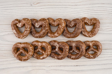 Gingerbread heart cookies on a wooden white background.