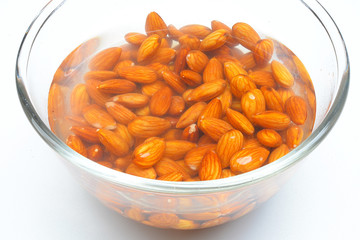 Raw almonds soaking in a white bowl of water
