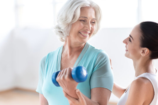 Happy pleasant woman holding a blue dumbbell