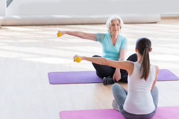 Calm elderly woman exercising on a yoga mat