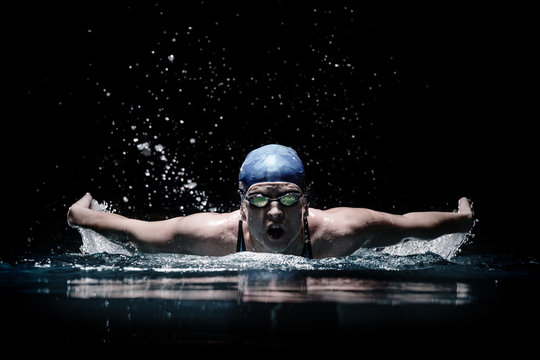 Profesional woman swimmer swim using breaststroke technique on the dark background
