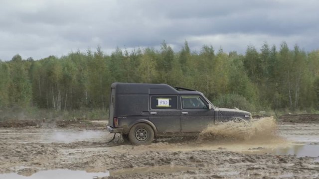 Jeep rides on a dirt road. The car enters the puddle of mud