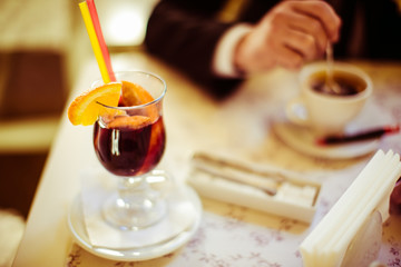 Glass with hot wine and slices of orange stands on the table