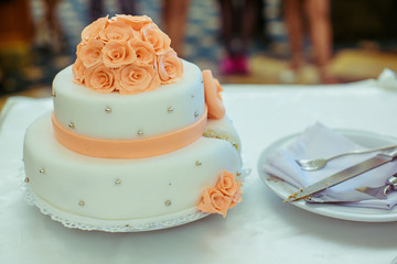 Obraz na płótnie Canvas Cut wedding cake decorated with orange glaze roses and silver pe