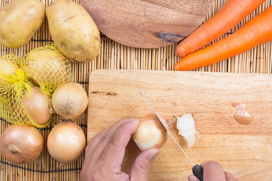Chef cutting the onion on a wooden board