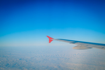 Obraz premium Wing of airplane flying above the clouds in the sky