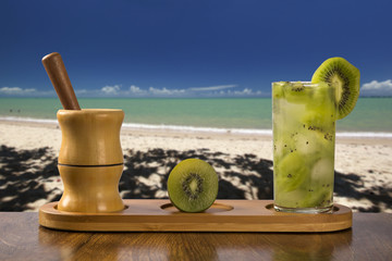 Kiwi Fruit Caipirinha of Brazil over beautiful beach background