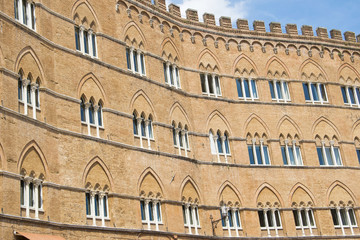 Fototapeta na wymiar Facade of a historic building with its windows on the square of Siena, Italy.