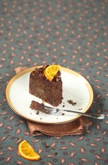 Piece of Vegan Chocolate Orange Truffle Cake on white plate, on grey background.