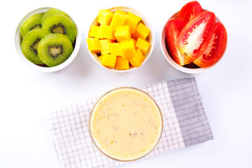 Top view of healthy mixed fruit mango kiwi and tomato smoothie on white background.