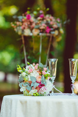 Champagne flutes stand behind pink flower bouquet on the round t