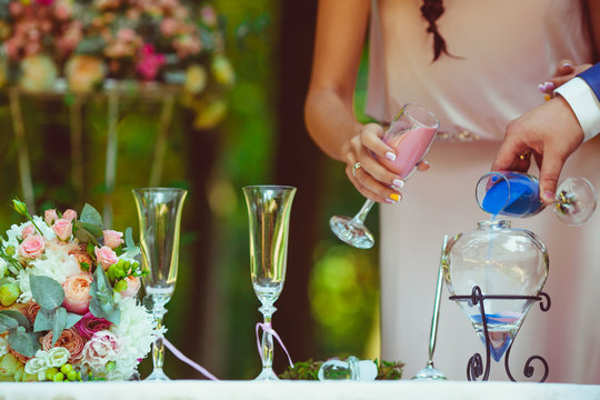 Bride and groom hold chamagne flutes with colored sand