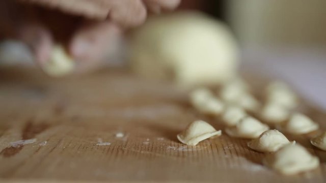 Uomo mezza et&agrave; che sta facendo la pasta fatta in casa su un tagliere di legno.