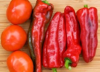 Red fresh pepper and tomato fruits on wooden Board
