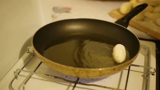 Crocchette di patate ripiene con prosciutto e provola che friggono in padella. 