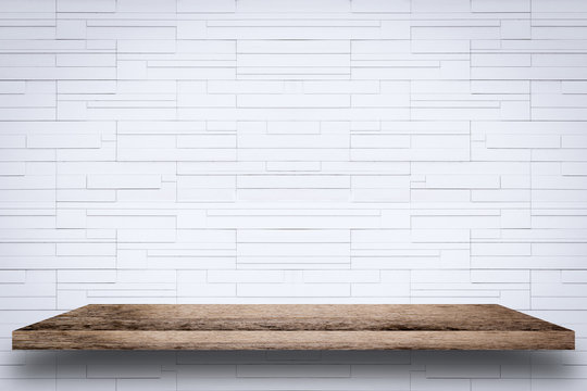 Empty wooden shelf with white brick wall background.