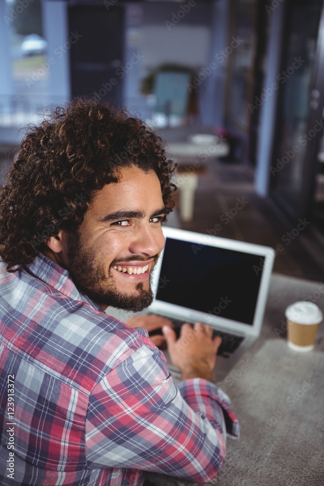 Poster Portrait of man smiling while using laptop