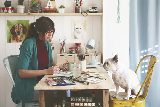 Artist painting an aquarelle of her French bulldog in her studio