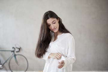 Young woman rolling up sleeve of her blouse