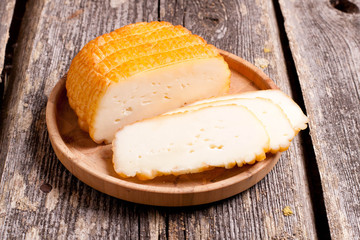 Home smoked rustic cheese on old board.